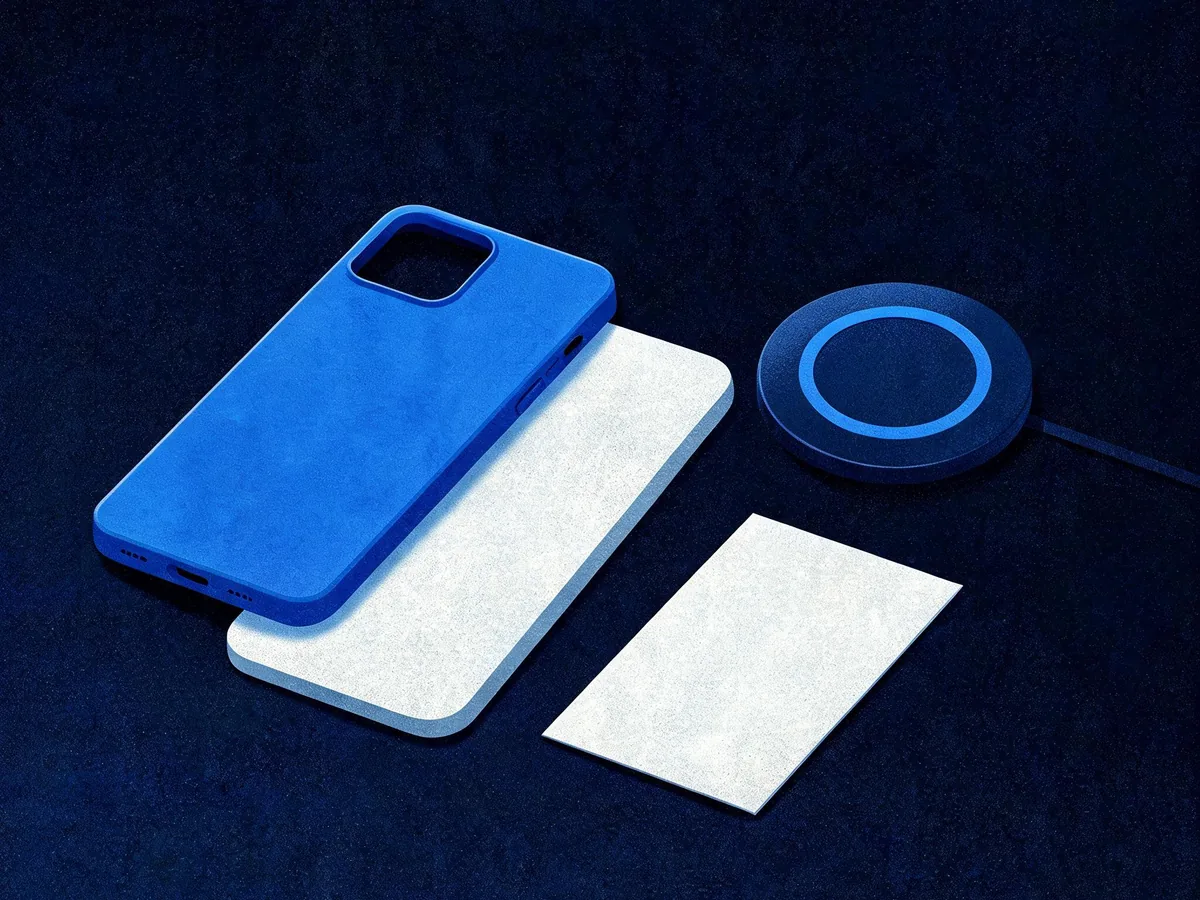 Cited — a close-up arrangement of a protective phone case, compatible device-shaped insert, charging pad, and care card on a workbench